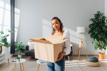 Young Woman With Cardboard Box Standing In New House