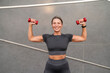 © Westend61 - Smiling mature woman exercising with dumbbells in front of wall
