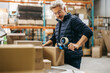 © Jacob Lund - Senior man taping cardboard boxes while fulfilling an order in a distribution warehouse