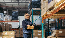 Thoughtful Senior Man Standing In A Warehouse With His Arms Crossed