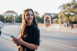 © Westend61 - Smiling young woman with mobile phone standing on road