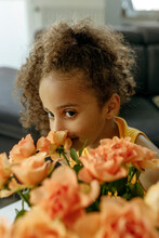 Smiling Girl Smelling Orange Roses At Home