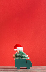 Aufkleber - Truck delivery christmas pine tree and santa hat on red background on wood table.Mockup banner with vertical space for design content