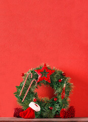 Wall Mural - christmas wreath decor with star,bauble,and candy cane,on copy space red wall on wood table