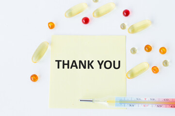 Wall Mural - Thank you text on a yellow card on a white background next to scattered tablets