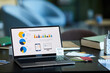 © Seventyfour - Screen of laptop with group of financial diagrams and illustrations standing on workplace of economist or broker in office