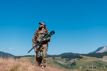 army soldier holding a sniper rifle with scope and walking in the forest. war, army, technology and people concept. 