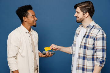 Side ivew young two friends happy fun men 20s wear white casual shirt together hold wireless modern bank payment terminal to process acquire credit card isolated plain dark royal navy blue background