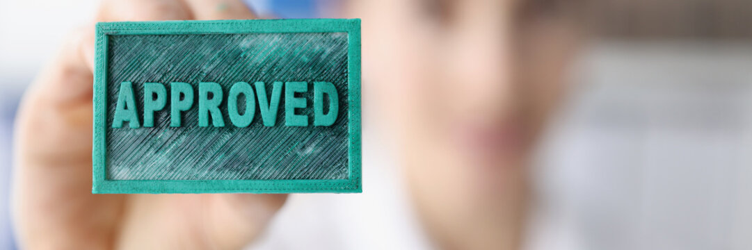 A woman holds a blue stamp inscription approved, close-up