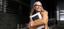 Portrait Of An Elderly Businesswoman With A Laptop In Glasses Outside The Office, Strong And Independent Woman Concept