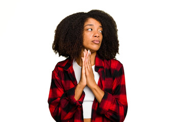 Young African American woman isolated praying, showing devotion, religious person looking for divine inspiration.