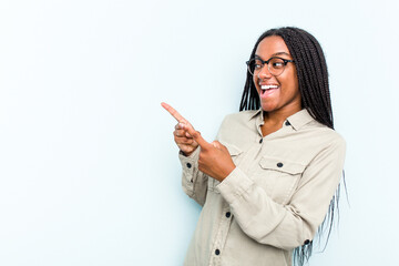Wall Mural - Young African American woman with braids hair isolated on blue background points with thumb finger away, laughing and carefree.