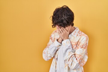 Sticker - Young man wearing casual summer shirt with sad expression covering face with hands while crying. depression concept.