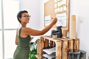 Sticker - Young hispanic woman smiling confident writing on corkboard at office