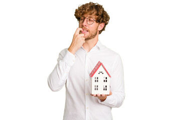 Business caucasian man holding toy house isolated on white background relaxed thinking about something looking at a copy space.