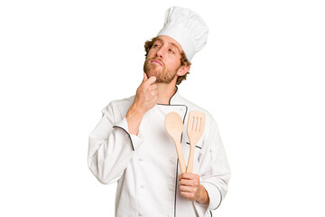 Young cook man isolated on white background looking sideways with doubtful and skeptical expression.