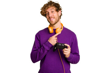 Young caucasian gamer man holding a game controller isolated on white background smiling and pointing aside, showing something at blank space.