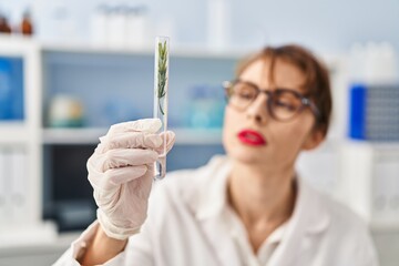 Sticker - Young caucasian woman wearing scientist uniform holding test tube at laboratory