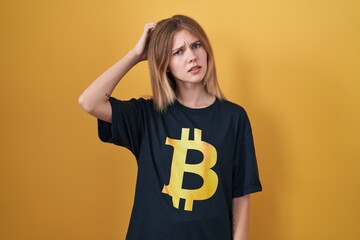 Sticker - Blonde caucasian woman wearing bitcoin t shirt confuse and wondering about question. uncertain with doubt, thinking with hand on head. pensive concept.