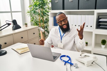 Poster - African american man working at medical clinic holding hammer celebrating victory with happy smile and winner expression with raised hands