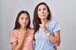 © Krakenimages.com - Young mother and daughter standing over white background thinking concentrated about doubt with finger on chin and looking up wondering
