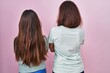 © Krakenimages.com - Young mother and daughter standing over pink background standing backwards looking away with crossed arms