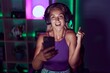 © Krakenimages.com - Young blonde woman playing video games with smartphone screaming proud, celebrating victory and success very excited with raised arm