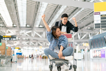 Happy smiling asian male and female waiting for flight and Check-in by mobile phone in terminal background.asian couple are traveling after the coronavirus 2019 (COVID-19) outbreak ends.