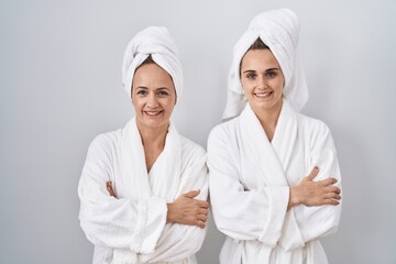 Canvas Print - Middle age woman and daughter wearing white bathrobe and towel happy face smiling with crossed arms looking at the camera. positive person.