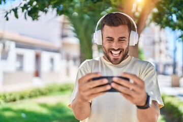 Sticker - Young hispanic man smiling confident playing video game at park