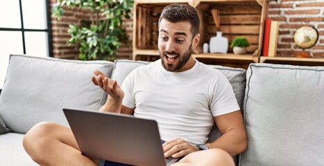 Wall Mural - Young hispanic man smiling confident having video call at home