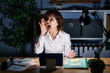 Sticker - Middle age woman working at the office at night shouting and screaming loud to side with hand on mouth. communication concept.