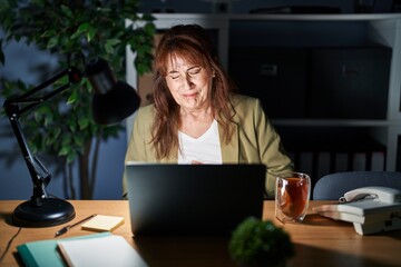 Sticker - Middle age hispanic woman working using computer laptop at night with hand on stomach because indigestion, painful illness feeling unwell. ache concept.