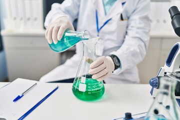 Poster - Senior man wearing scientist uniform pouring liquid at laboratory