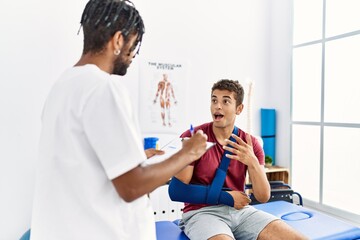 Canvas Print - Two men physiptherapist and patient having rehab session writing accident report at clinic