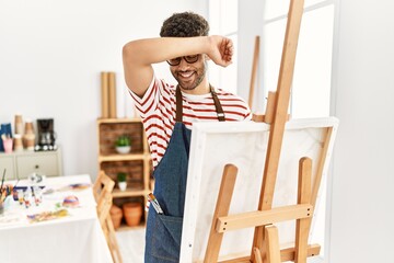 Canvas Print - Arab young man at art studio smiling cheerful playing peek a boo with hands showing face. surprised and exited