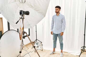 Wall Mural - Arab young man posing as model at photography studio puffing cheeks with funny face. mouth inflated with air, crazy expression.