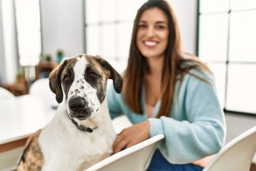 Young woman smiling confident sitting on table with dog at home