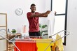 © Krakenimages.com - Young african american man smiling confident holding clean clothes at laundry room