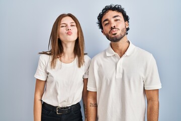 Canvas Print - Young couple wearing casual clothes standing together looking at the camera blowing a kiss on air being lovely and sexy. love expression.