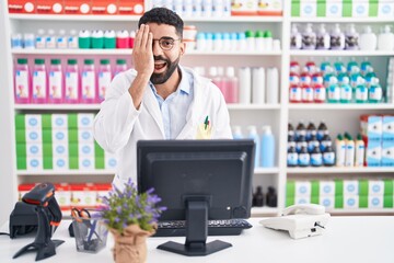 Wall Mural - Hispanic man with beard working at pharmacy drugstore covering one eye with hand, confident smile on face and surprise emotion.