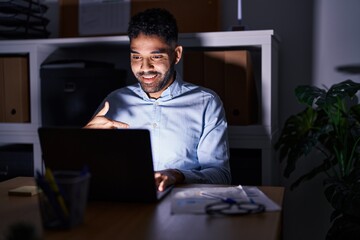 Wall Mural - Hispanic man with beard working at the office with laptop at night pointing finger to one self smiling happy and proud