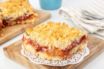 Wall Mural - Portion of crumbly shortbread pie with plum and apple jam on wooden board. Dessert with fruit and streusel.