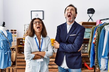 Poster - Two hispanic people working as manager at retail boutique angry and mad screaming frustrated and furious, shouting with anger looking up.