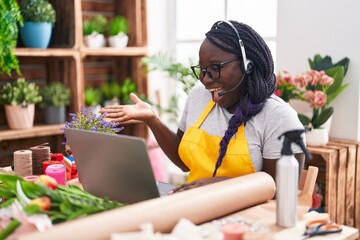 Poster - Young african woman working at florist shop doing video call celebrating achievement with happy smile and winner expression with raised hand