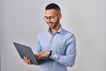 Wall Mural - Young hispanic man working using computer laptop with a happy and cool smile on face. lucky person.