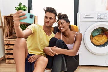 Canvas Print - Man and woman couple make selfie by the smartphone waiting for washing machine at laundry room