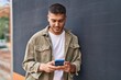 © Krakenimages.com - Young hispanic man smiling confident using smartphone at street