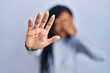 © Krakenimages.com - African american woman standing over blue background covering eyes with hands and doing stop gesture with sad and fear expression. embarrassed and negative concept.
