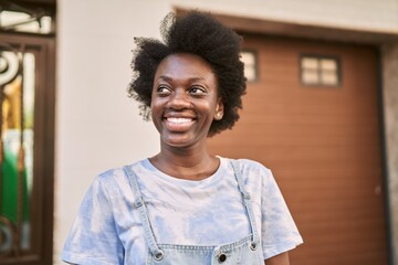 Wall Mural - Young african woman smiling confident at street